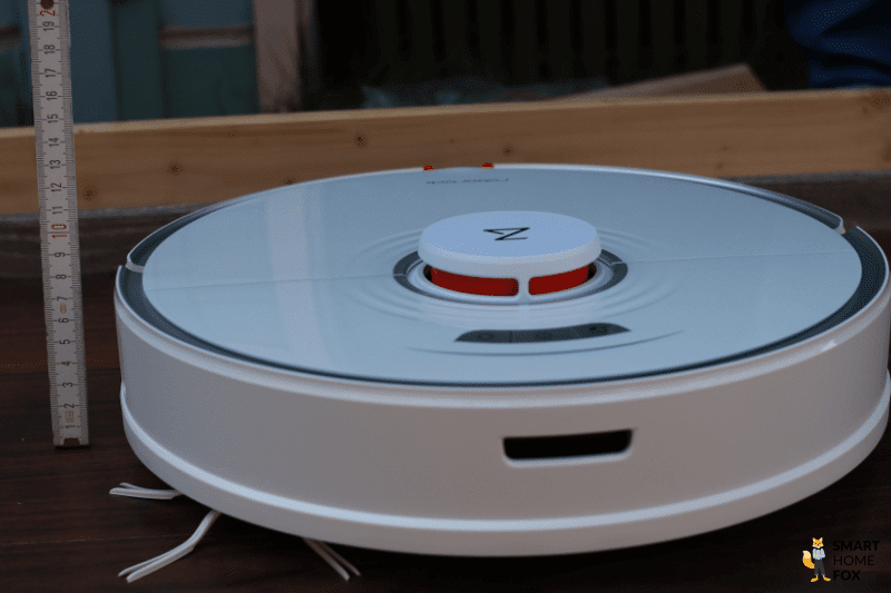 Ein Saugroboter mit einem Lasernavigationsturm wird mit einem Lineal ausgemessen.